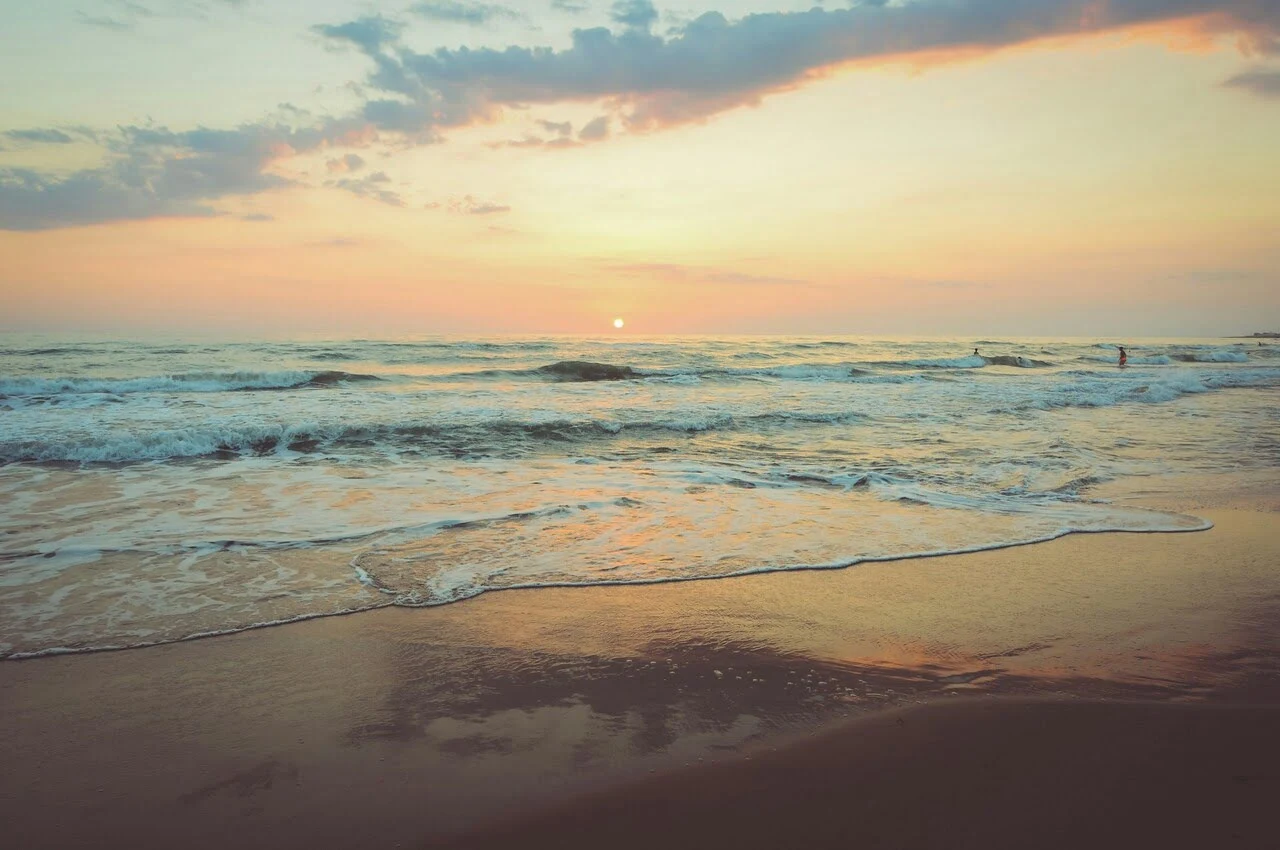 a beach with waves and a sunset