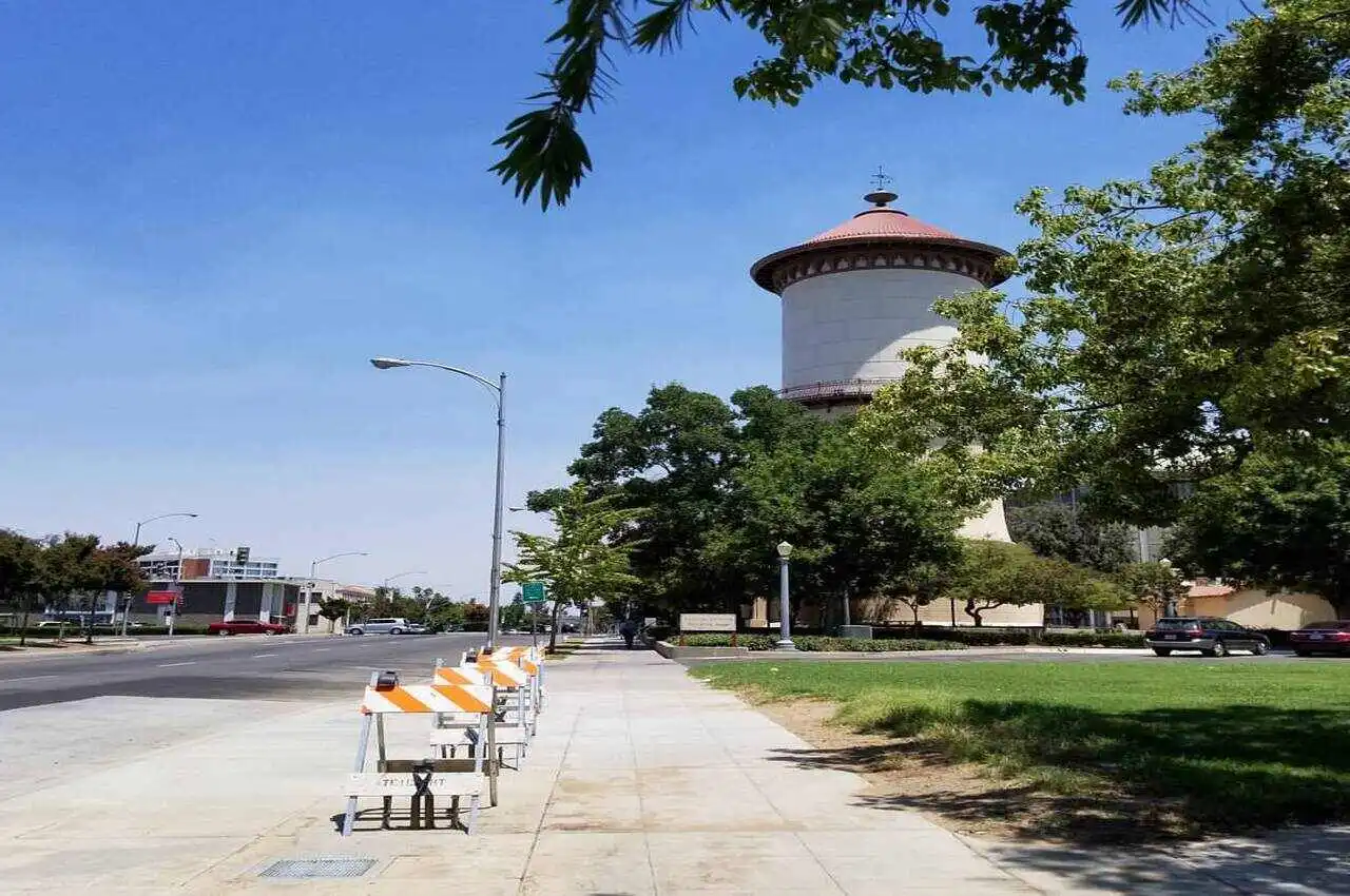 A tall tower with a green park and a road on the side.