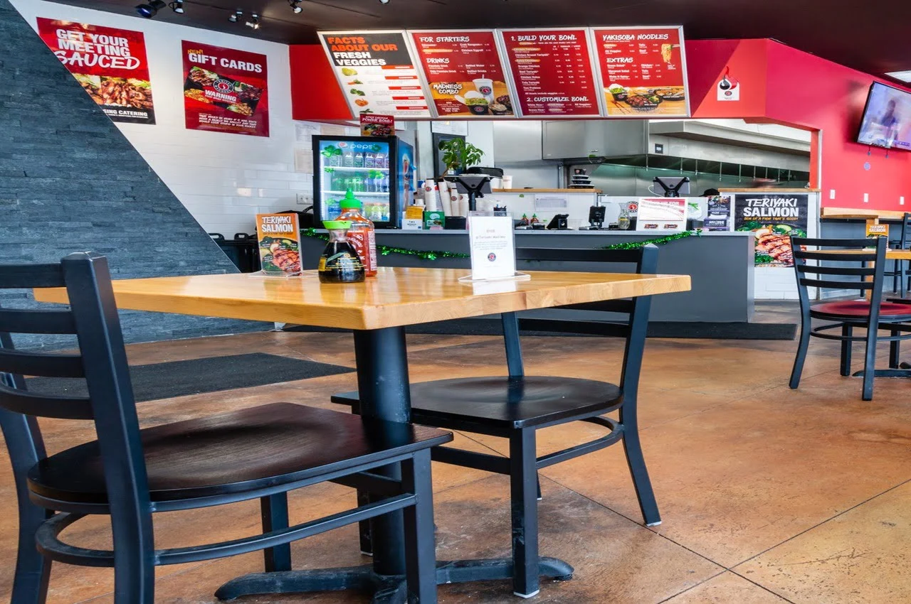 Seating area of a restaurant with menu display on the back.
