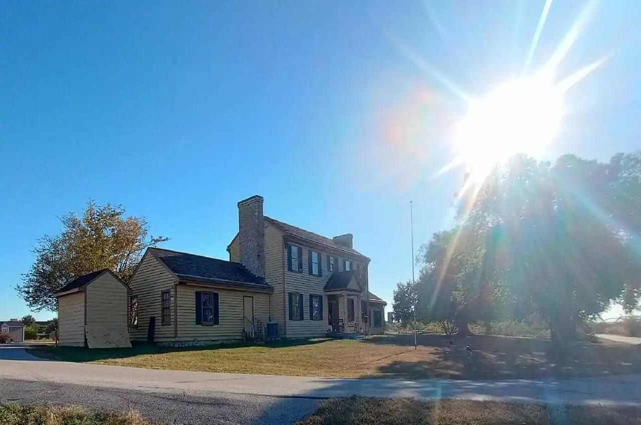 A house in a distance with grass on the other end of the road.