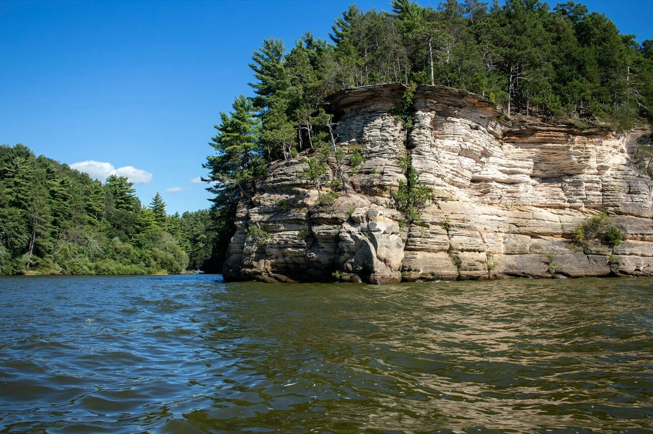 A river with a big rock in the middle and an island covered with trees.