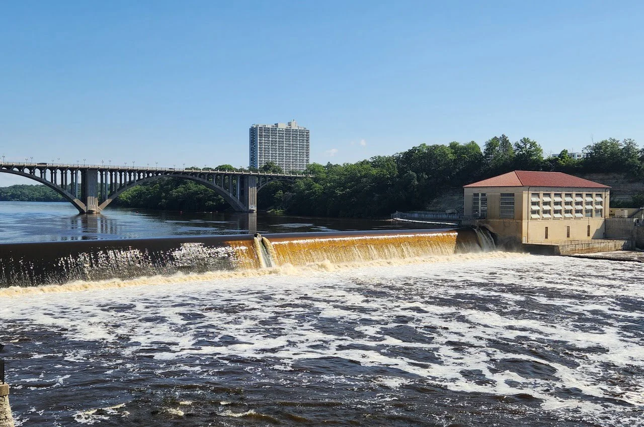 A flowing river with a dam and bridge on top of it.