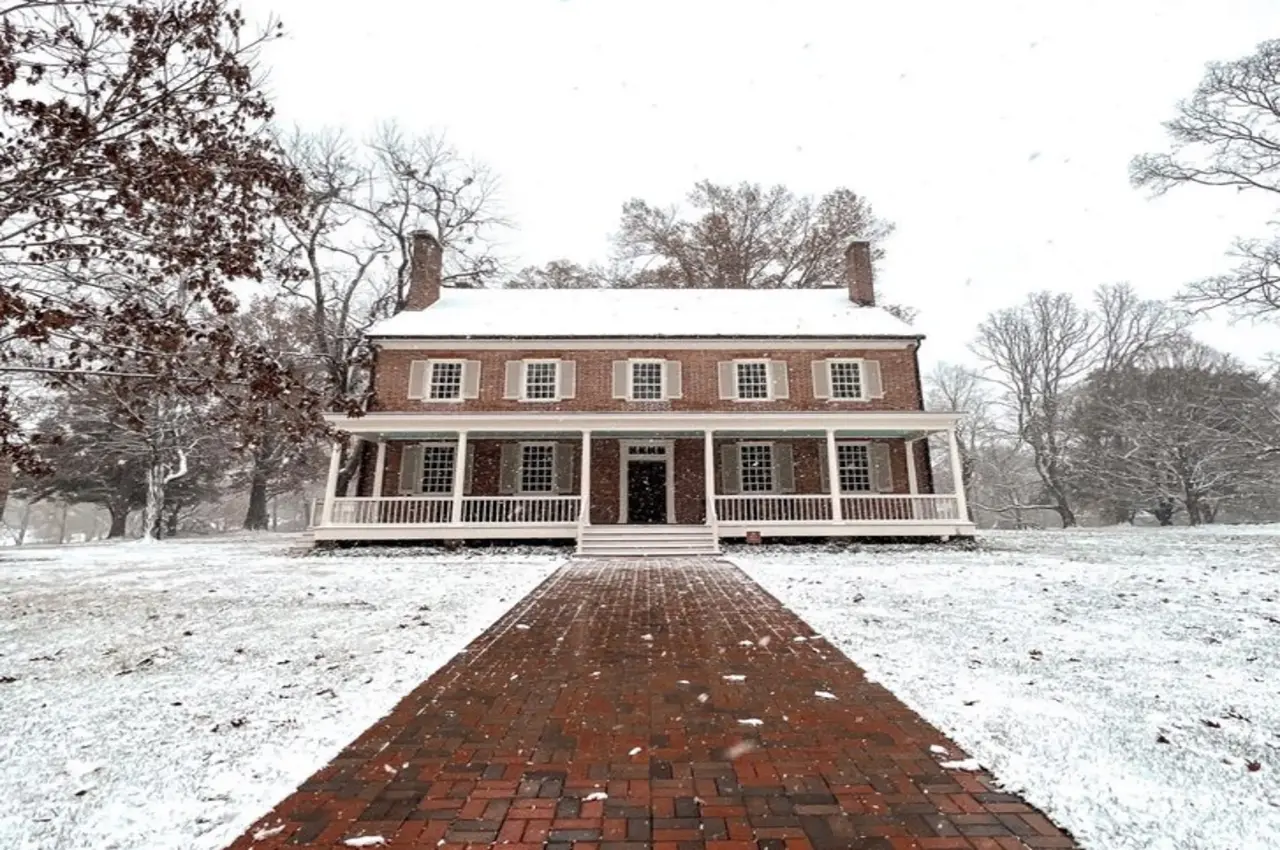 a brick walkway leading to a house with snow on the ground