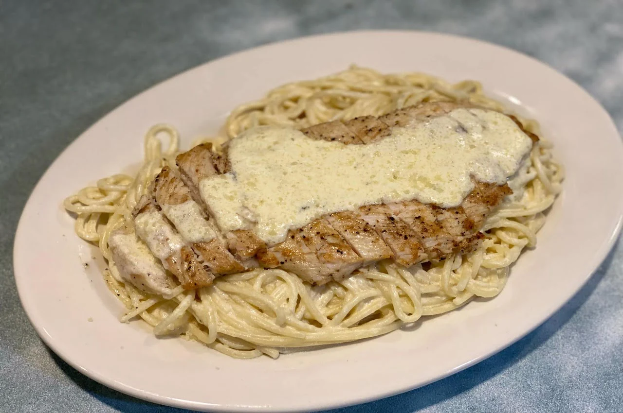 Pasta with a piece of chicken and sauce on top.