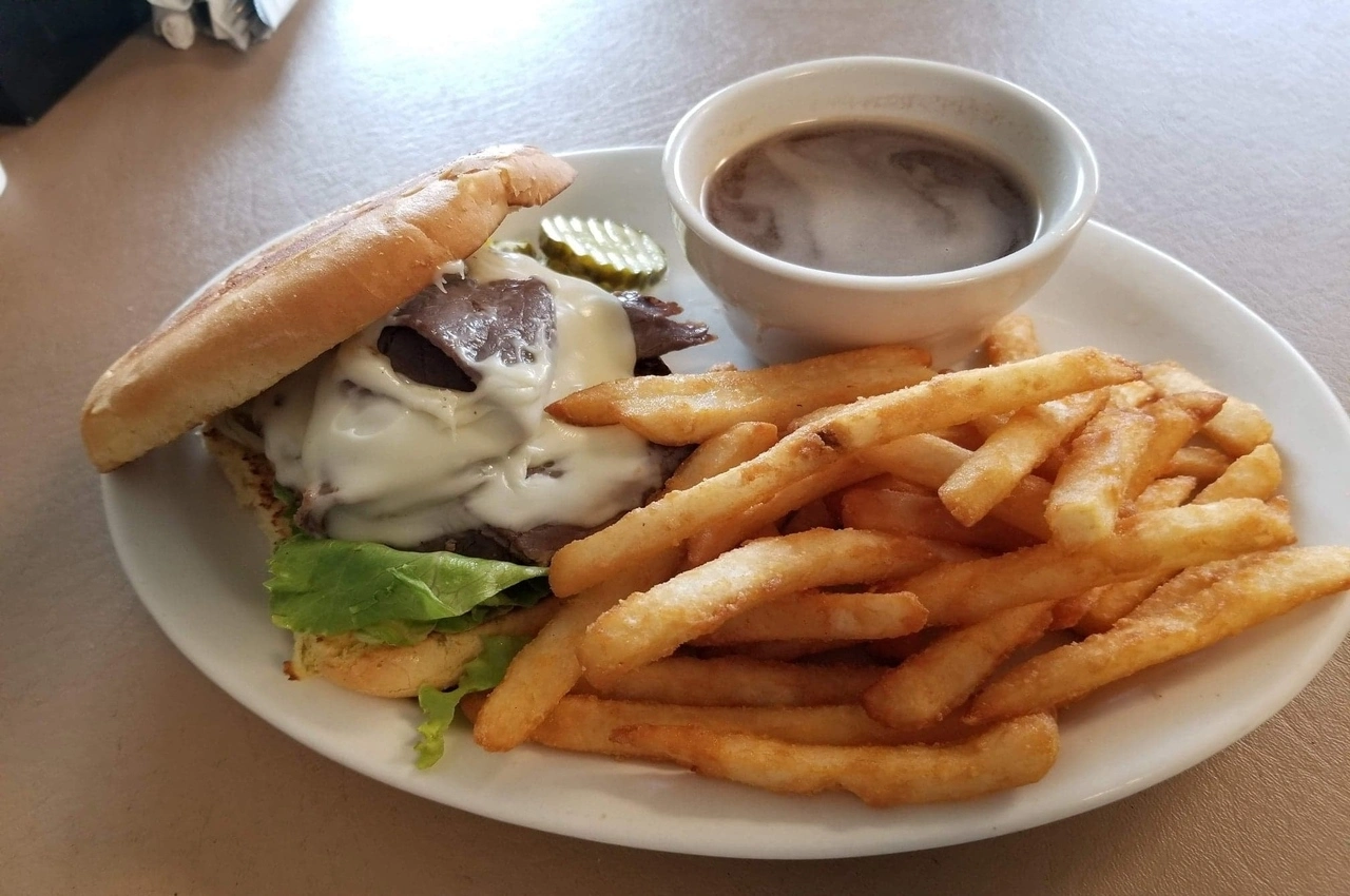 A plate whole of French fries, sandwich and gravy.