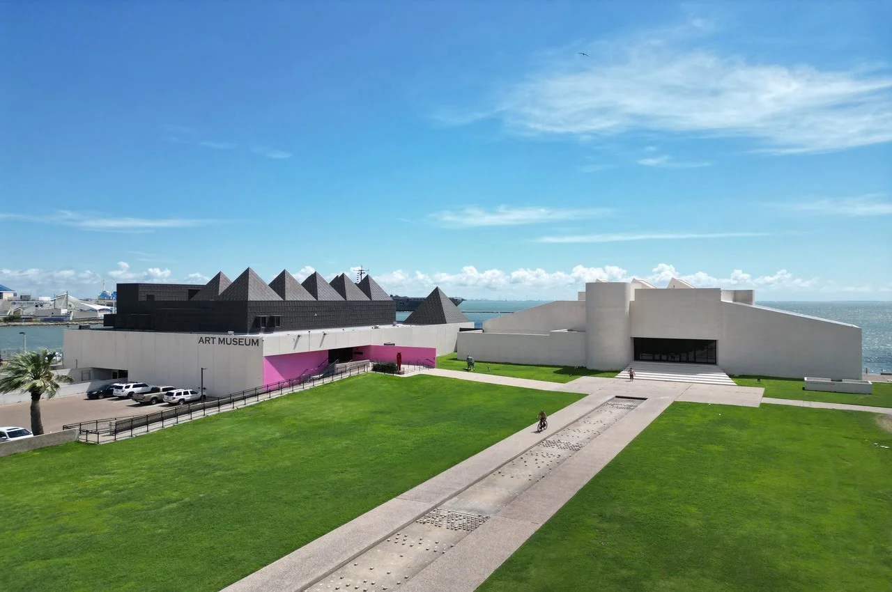 Two sections of a museum with cars parked nearby