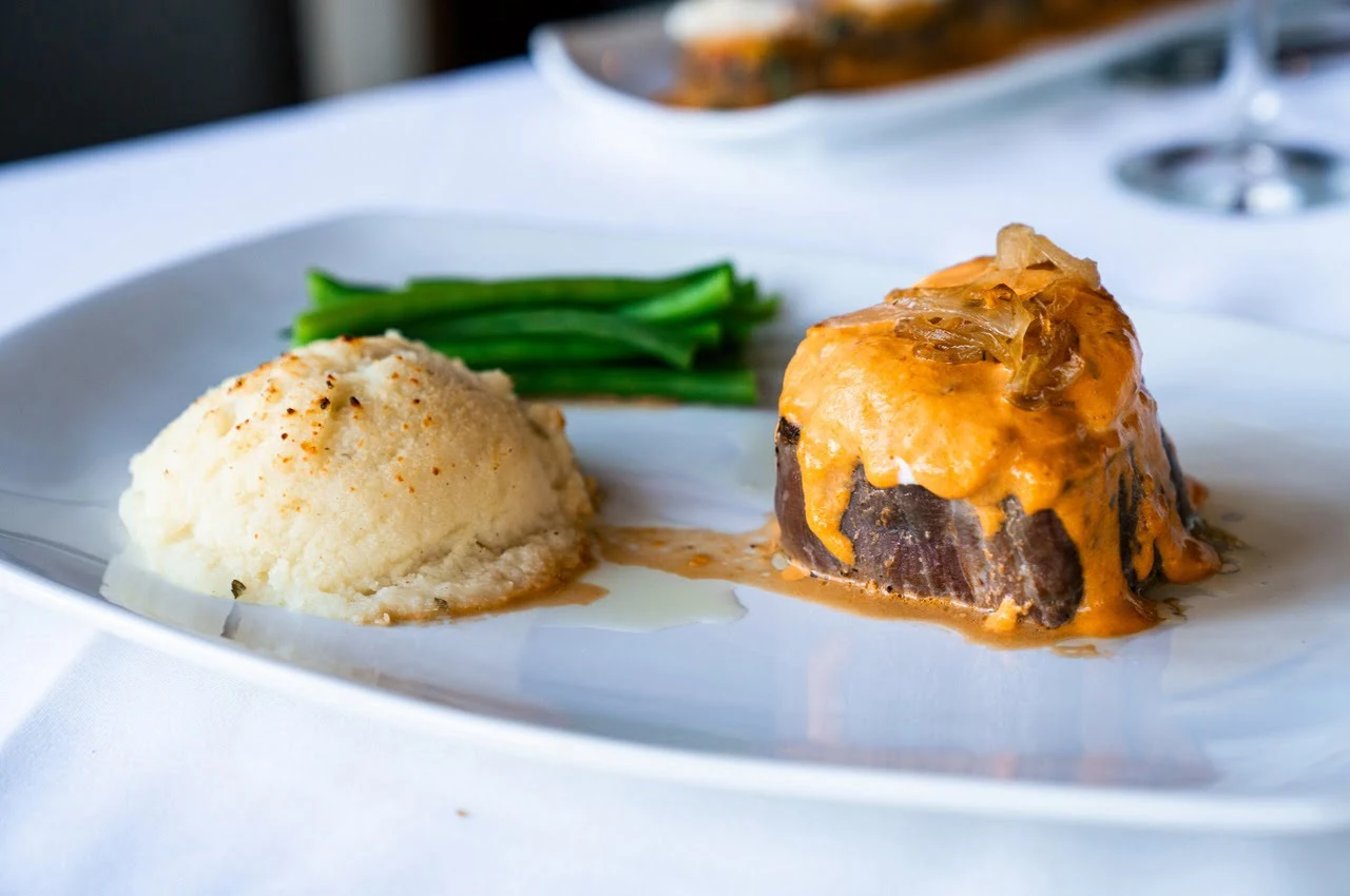 Smash potato and a piece of meat on the plate.

