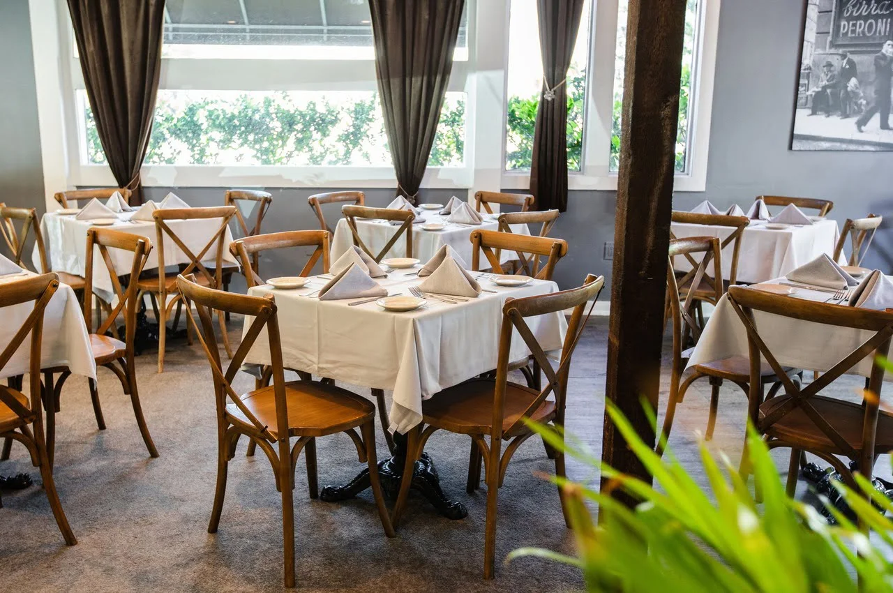 Wooden chairs with a table with a white sheet.