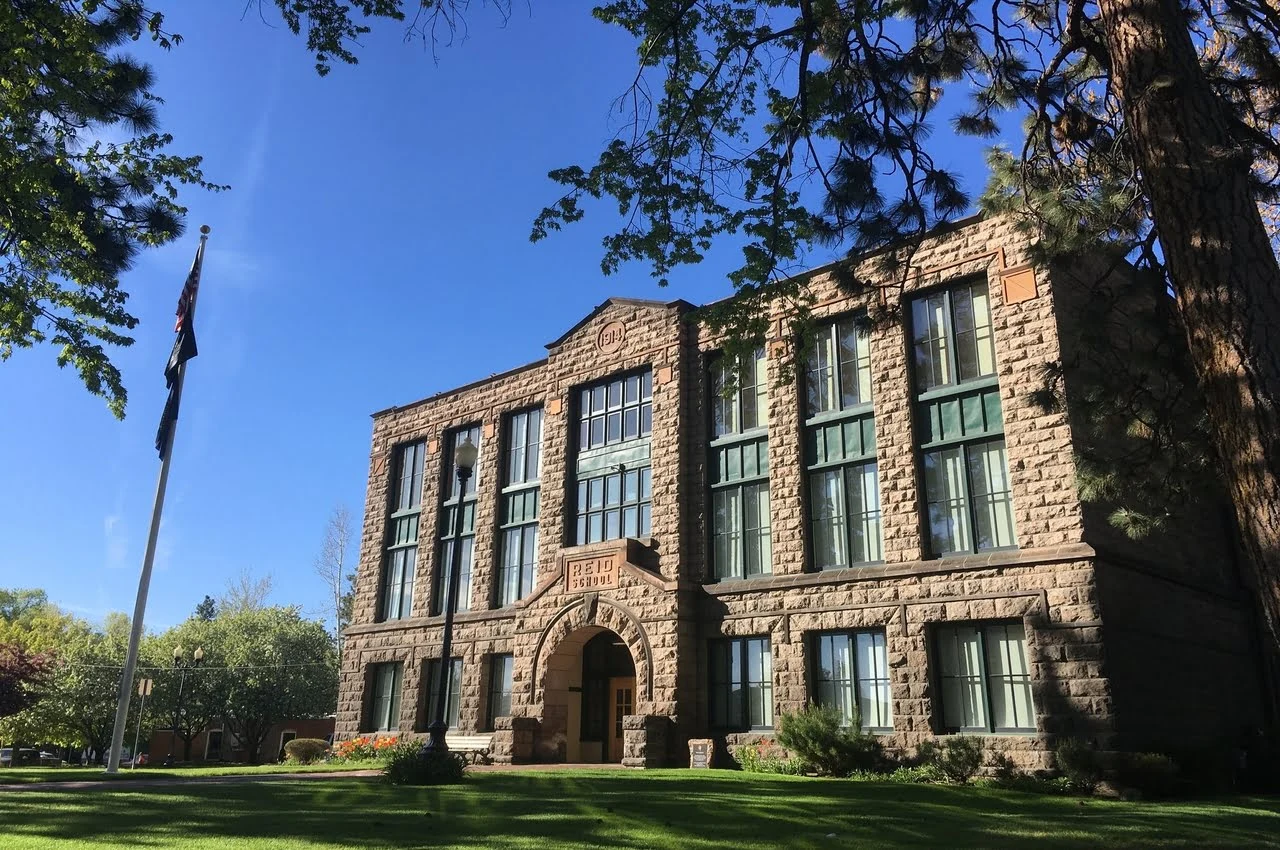 A brick-designed building with a tree in front.