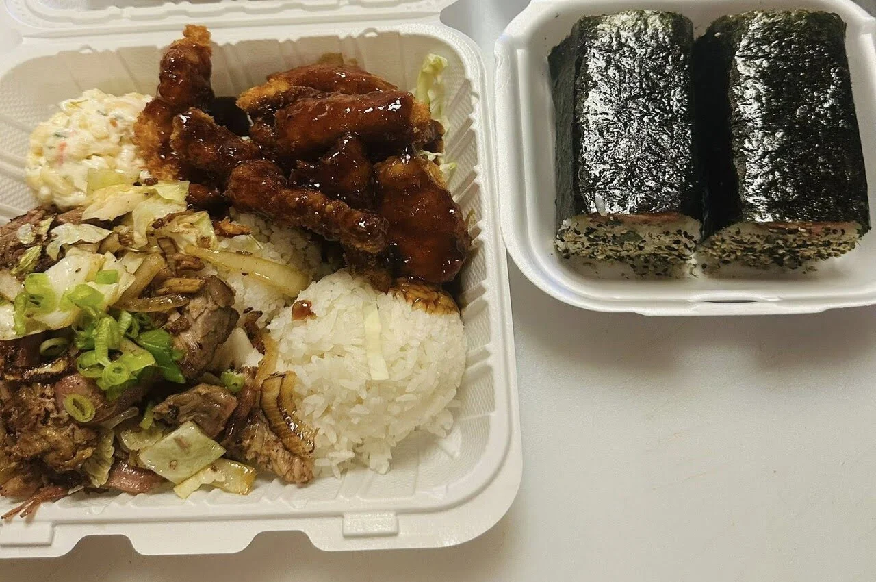 Sushi, boiled rice, and gravy in a take-out box.